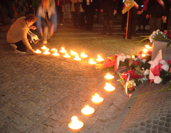 Znicze układane przy grobie Polaków tworzą wielki ognisty krzyż